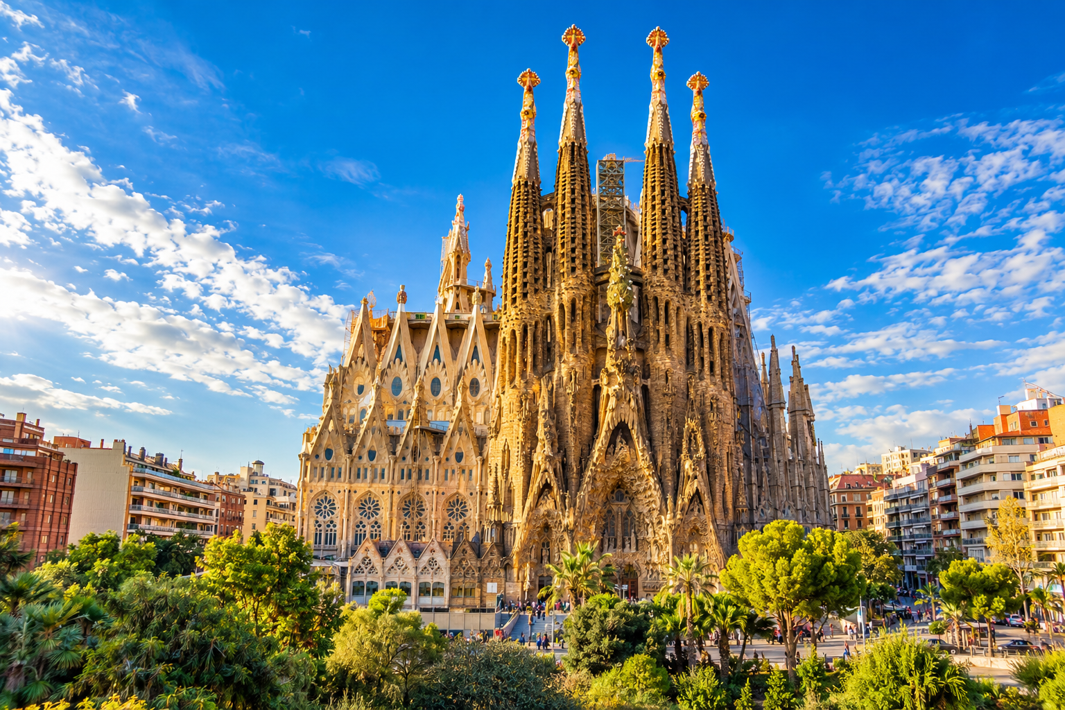 The magnificent Sagrada Família Basilica with its towering ornate spires under a bright blue sky in Barcelona, Spain.